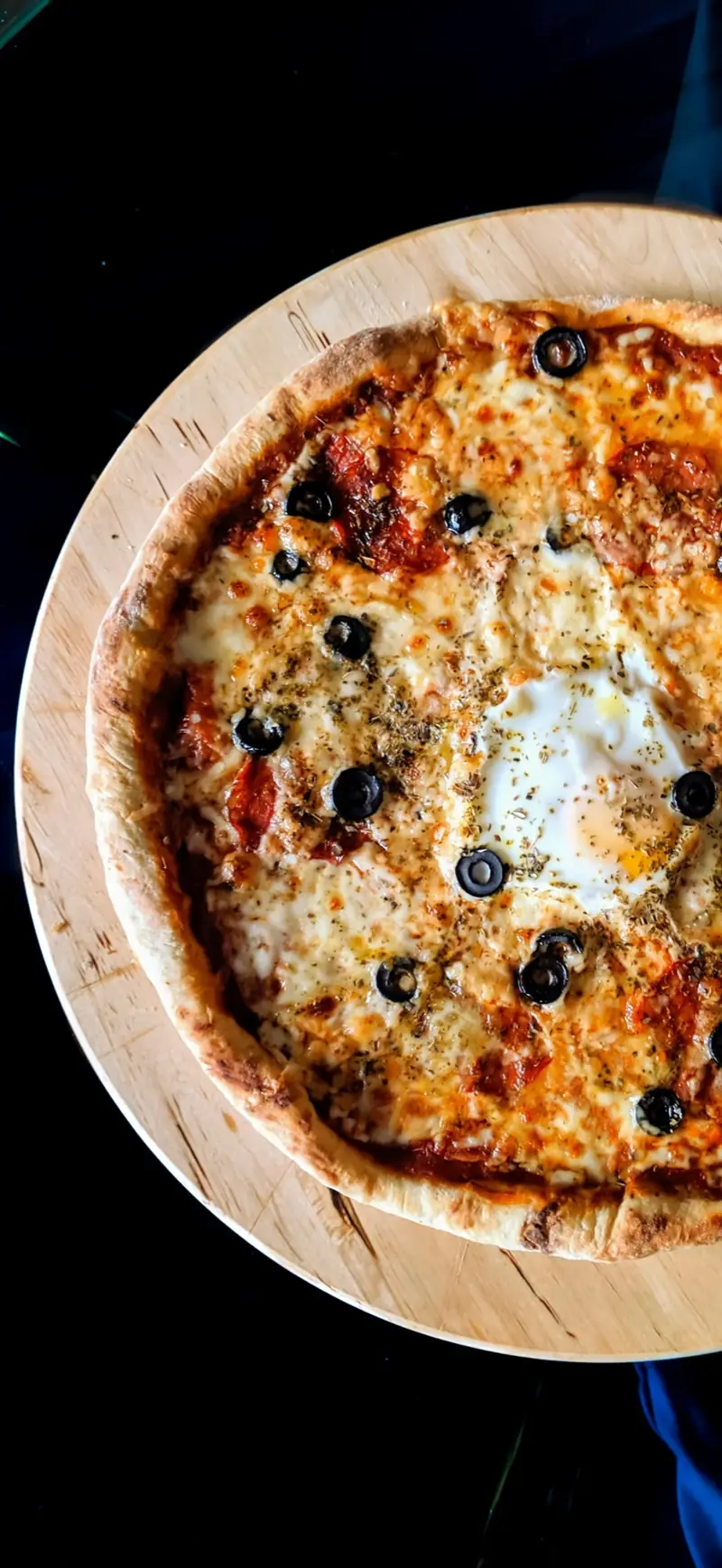Pizza auf einem Holzteller, von oben fotografiert
